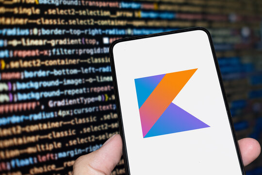 Kotlin logo sign on the smartphone screen with code background. London, UK, 11.14.2024