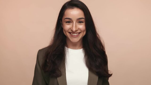 A playful and suggestive hand gesture of air kisses convey a message of flirting and affection on a plain brown background.