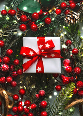 Christmas concept background. Top view of white gift box with red stars bow and a red berries branches
