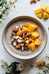 A bowl of chia pudding topped with sliced almonds and fresh mango
