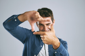 Man, smile and finger frame in studio portrait with photography icon with fashion by white background. Person, model and shape with hands, perspective and happy with sign for memory in Argentina