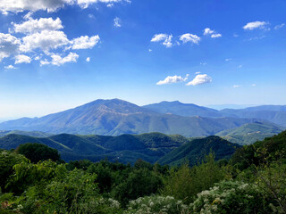 This stunning mountain landscape near Xanthi offers a serene view of rolling green hills and distant peaks under a vibrant blue sky.