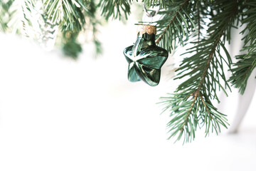 Modern glass Christmas tree decoration on a branch on a white background. Space for text.