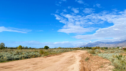 View of the rural dirt road leading to the mountains. Adventure and tourism, trekking. Summer in Kyrgyzstan. Travel to Asia. Beautiful landscape. Blue sky