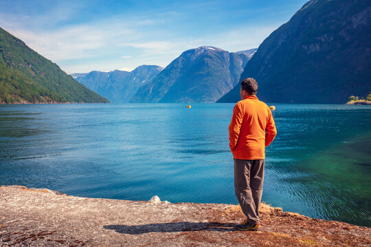 A human stands on the embankment in Hellesylt and looks at Geirangerfjord. Norway, Europe