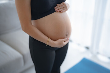 Pregnant asian woman holds hands on belly touching her baby caring about her health Beautiful happy pregnant woman&nbsp;tender mood photo of pregnancy.