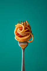 Spaghetti on a fork with tomato sauce against turquoise background