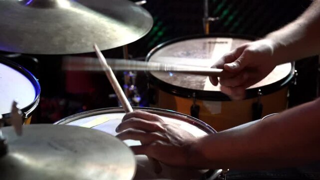 Drummer playing a snare drum with two sticks in a dark environment, creating rhythmic beats and energetic sounds