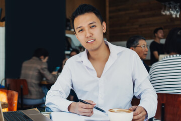 Asian man working on laptop in cafe
