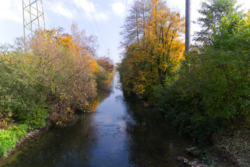 Obraz premium Diminishing perspective of Glatt River with autumn trees and power line in the background at Swiss City of Zürich on a sunny autumn day. Photo taken November 8th, 2024, Zurich, Switzerland.