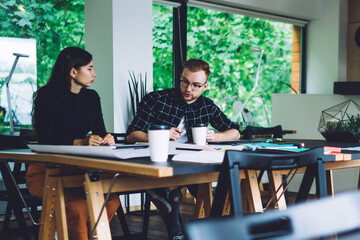 Male and female colleagues collaborating on education information spending learning day in modern coworking space with comfortable workplace, concept of brainstorming and knowledge studying