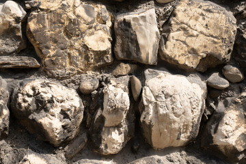 Close up of texture of old stone wall with big boulders of limestone in different pastel colors.