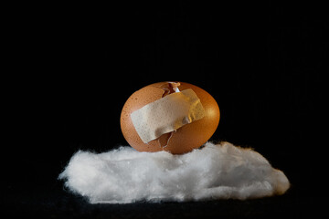 Broken egg shell with repair patch placed on a wadding cloud. Concept of fragility and resilience