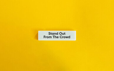 Stand Out From The Crowd. Text on Block Letter Tile on Yellow Background. Minimal Aesthetic.