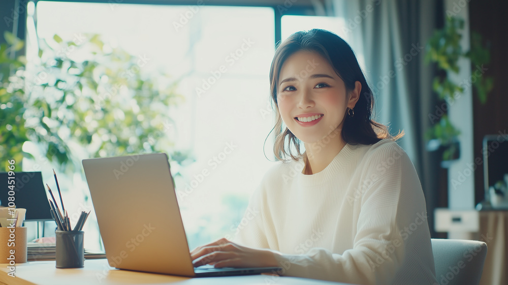 Poster 若くてかわいいアジア人女性が、デスクでパソコン作業をしている。笑顔のビジネスシーンの撮影。