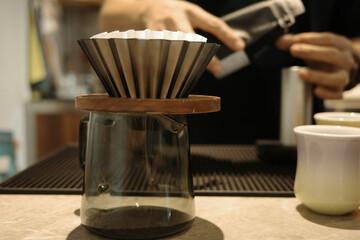 A barista is making hand-brewed coffee in a coffee shop