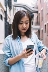 Asian young lady messaging in social network during walk