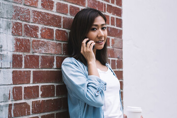 Asian cheerful woman calling on cellphone on street