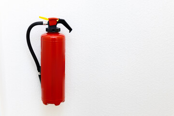 Naklejka premium a red fire extinguisher mounted on a white wall with a large clear space on the side, drawing attention to the importance of safety. The minimalist layout emphasizes the role of the fire extinguisher 