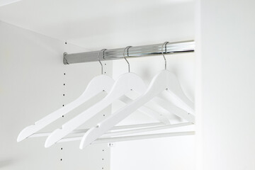 white wooden hangers hanging in an empty white closet, creating a clean and spacious feel. Emptiness and monotony emphasize the minimalism and readiness of the closet for organization and order.