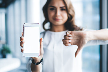 Obraz premium Modern disappointed female office worker using smartphone in office