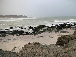 a rocky shoreline adds texture, while the open sea stretches out under a clear sky, giving a sense of openness and natural power.