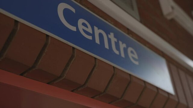 A blue sign with the word CENTRE written on it. The sign is on a brick wall