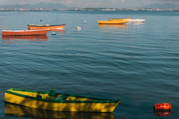 Fototapeta premium Colorful boats floating on calm water with distant mountains.