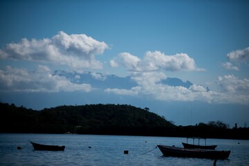 Boats on calm water with mountain and hill backdrop