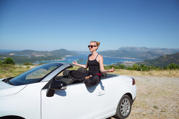 woman in zen pose on car. killing in any convenient place. meditation