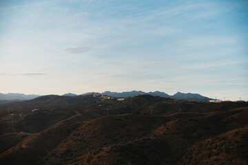  Expansive view of rolling hills with distant mountain peaks, framed by a clear sky and peaceful landscape