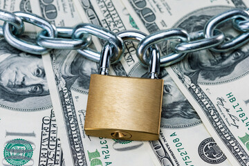 Chain with lock on the dollar banknotes. Business safety or financial protection or restriction access or ban dollars.