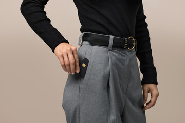 female hand putting black premium credit bank card in pants pocket. Money finance