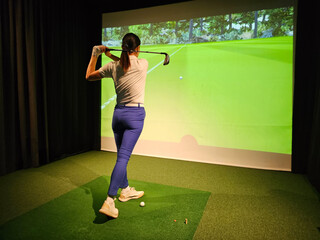Female golfer plays golf on golf simulator concept