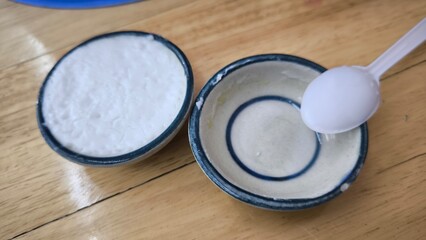 coconut milk custard in small porcelain cup (Thai dessert) in wooden dish on table.