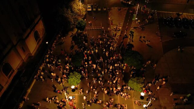 Aerial top down shot of crowds of people dancing in the streets at night. high angle drone footage of people street dancing salsa, bachata, west coast swing and tango seen from above. Open air music
