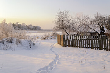 Winter landscape, wooden fence in the countryside area by winter sunset, winter landscape view