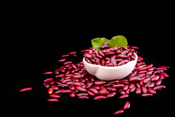 Raw red kidney beans in wooden bowl on black table, closeup