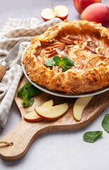 Delicious homemade apple galette with almond flakes and fresh mint on rustic background