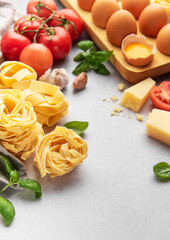 Fresh pasta, tomatoes, garlic, cheese, eggs and basil creating italian food background