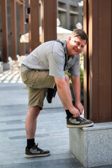 man lacing up summer shoes with his foot on the curb.