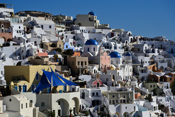 Ein schöner Blick auf die typischen weißen Häuser von Oia auf der Griechischen Insel Santorin. Aber es sind auch vereinzelt bunte Häuser zu sehen, sowie die markanten blauen Kuppeln der kirchen.