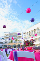 Wedding reception in a resort garden decorated with purple, pink, and white colors, creating a vibrant and festive atmosphere