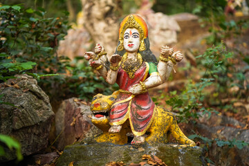 Durga maa forest indian goddess, sacred idol in jungle, nature-surrounded deity statue, van devi idol in forest, ancient temple in woods, rural deity sculpture, forest shrine stock photo.

