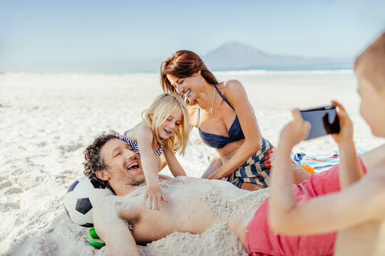 Happy family having fun with sand at the beach
