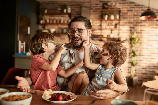 Father enjoying breakfast time with two young sons in cozy kitchen