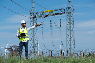 Male engineers  against substation  on wind turbine farm.