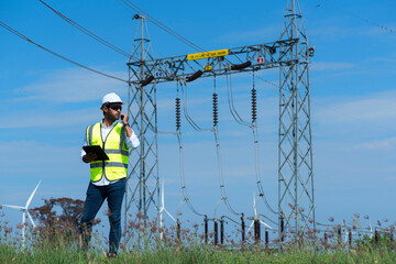 Male engineers  against substation  on wind turbine farm.