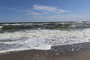Ocean Waves Crashing onto Sandy Shore under Blue Sky