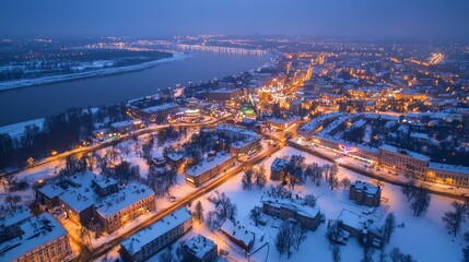 Aerial view of a city covered in snow at night with a river running through it.